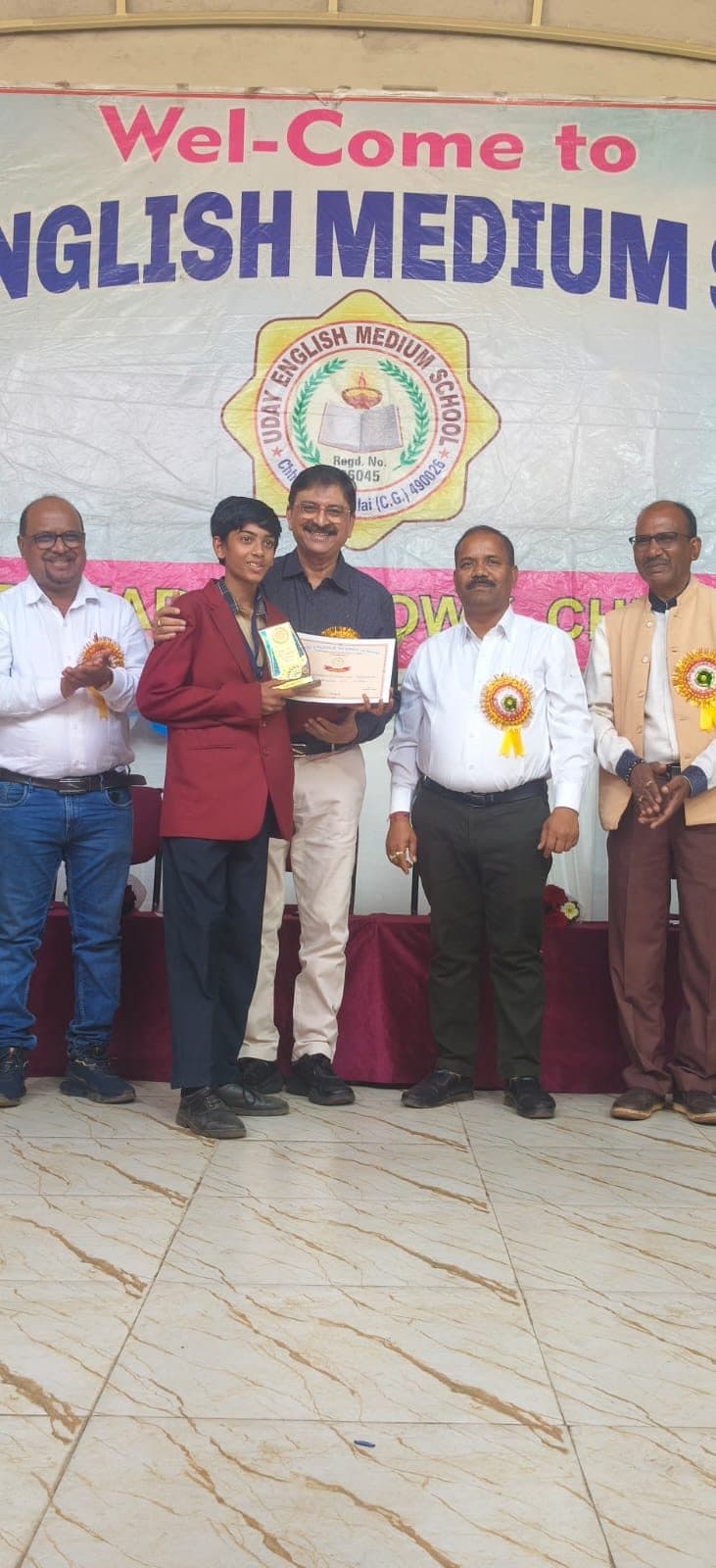 A senior student being felicitated on stage in front of the school crest