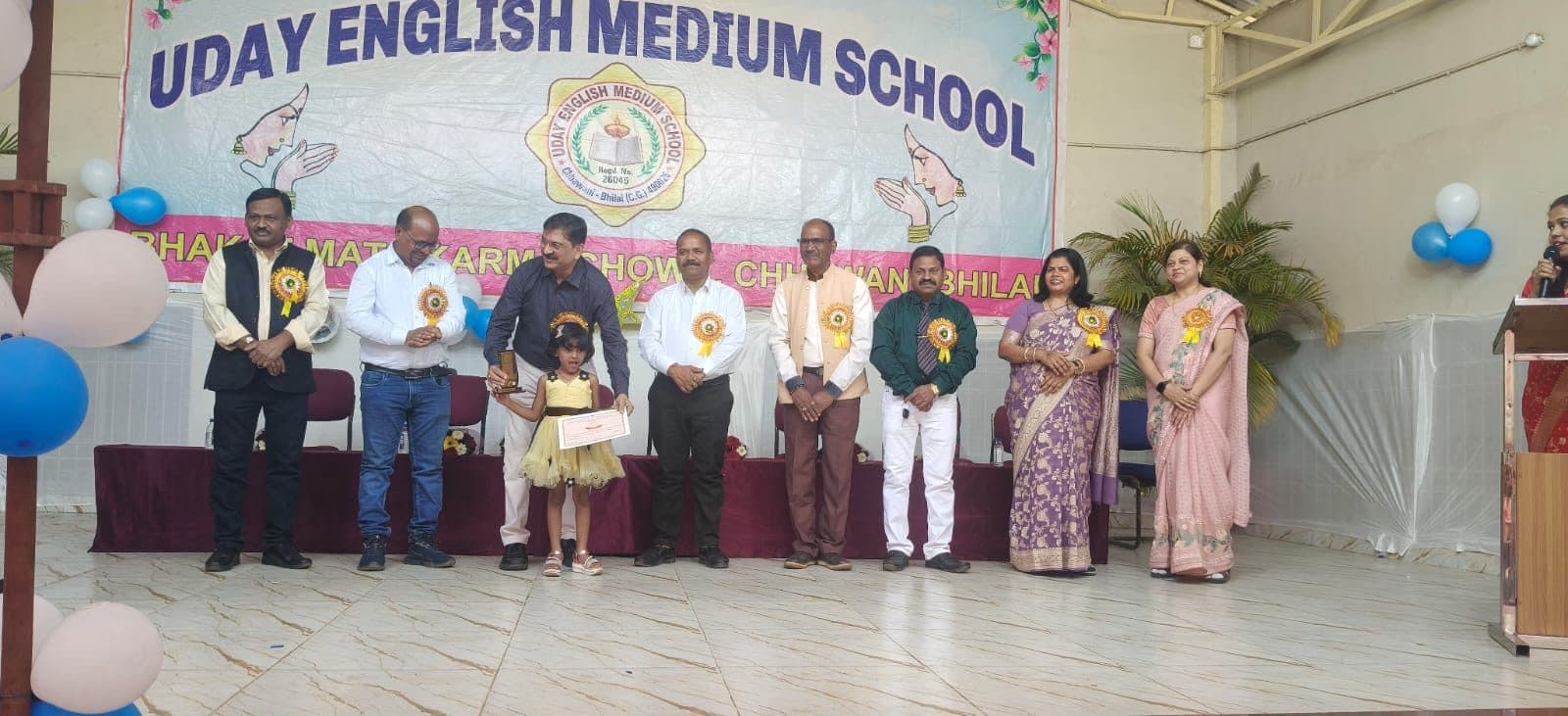 A young student receiving a trophy on stage at the school's annual function