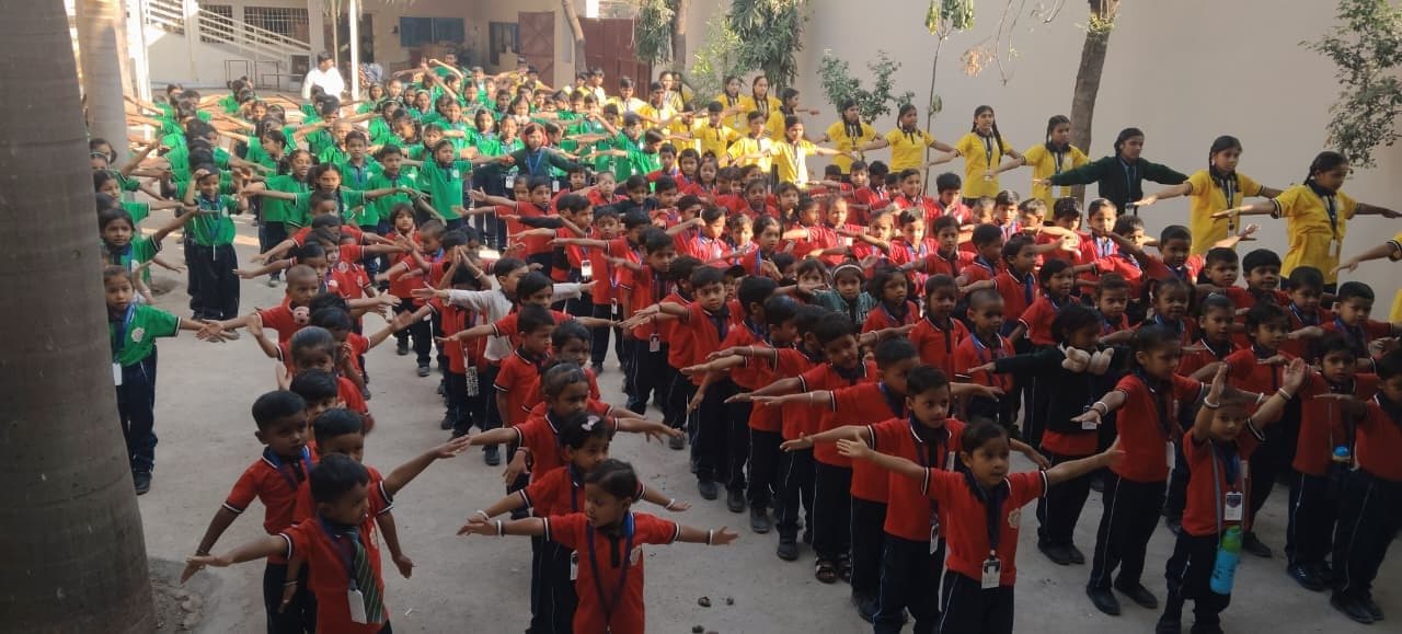 Students in house uniforms standing arms-length apart during morning assembly