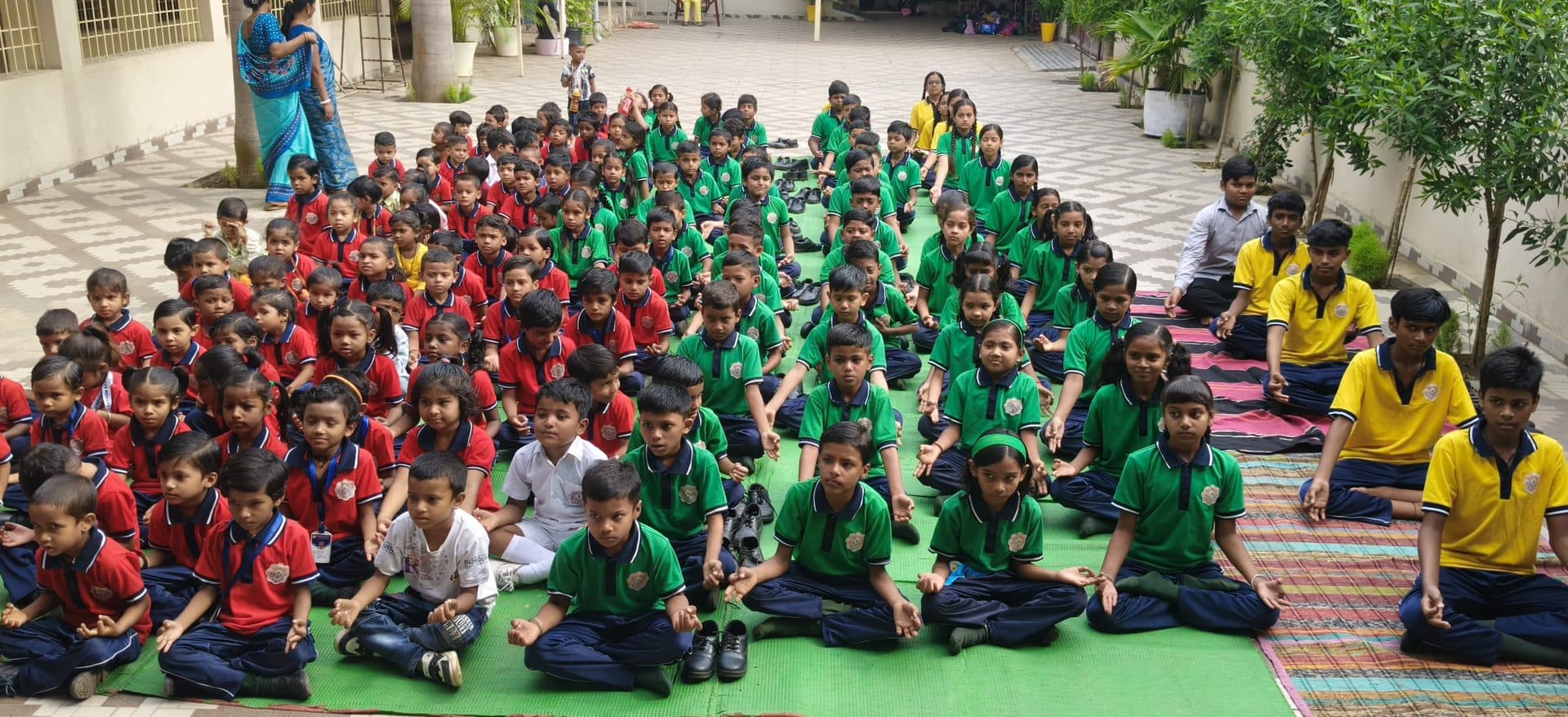 The whole school seated on mats in the courtyard for a group meditation session
