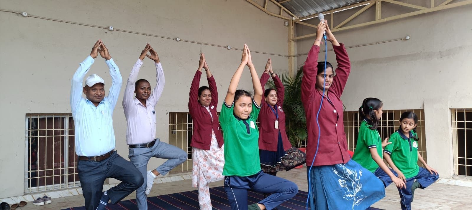 Students and teachers holding the tree pose together on Yoga Day